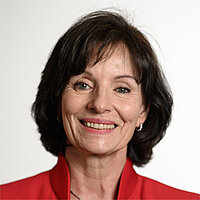 Roswitha Pfeiffer Die Frau ist mittleren Alters und hat kinnlange dunkelbraune Haare. Sie trägt einen roten Blazer.
